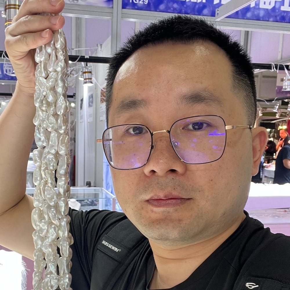 Mike, founder of Lass Pearl, holding a strand of baroque freshwater pearls at a wholesale market