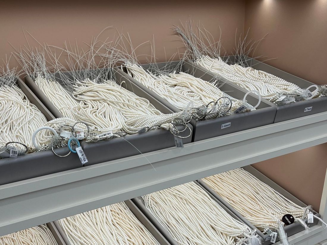 Trays of white freshwater pearl strands grouped by size and grade in a display case