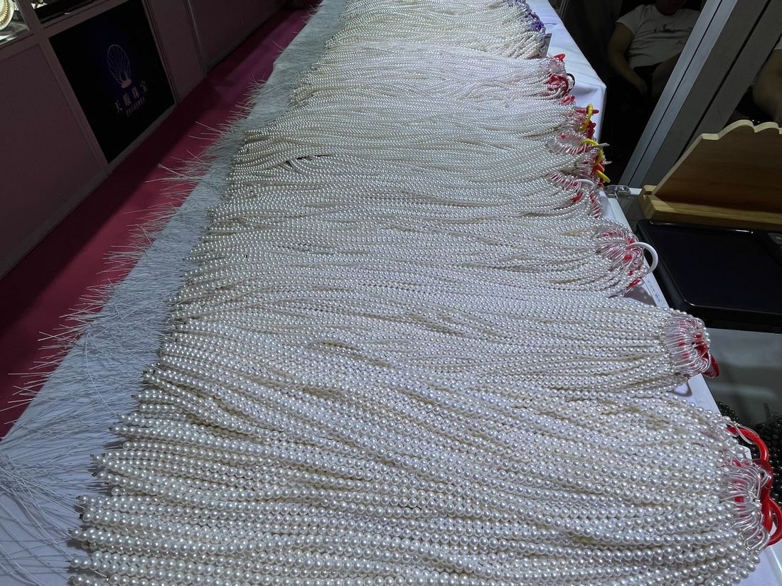 Long table of white freshwater pearl strands laid out for comparison